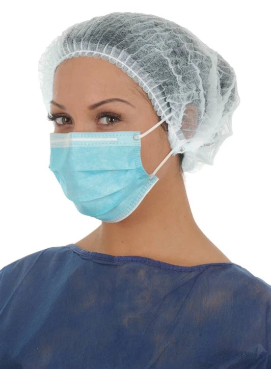 soignante avec un masque, une charlotte et une blouse visiteur